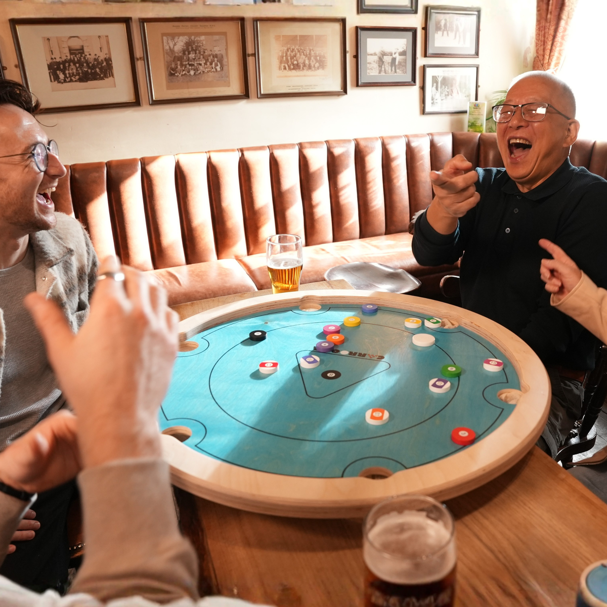 Vrienden lachen tijdens een potje Carrooka Pool 8 Blue aan een tafel in de pub