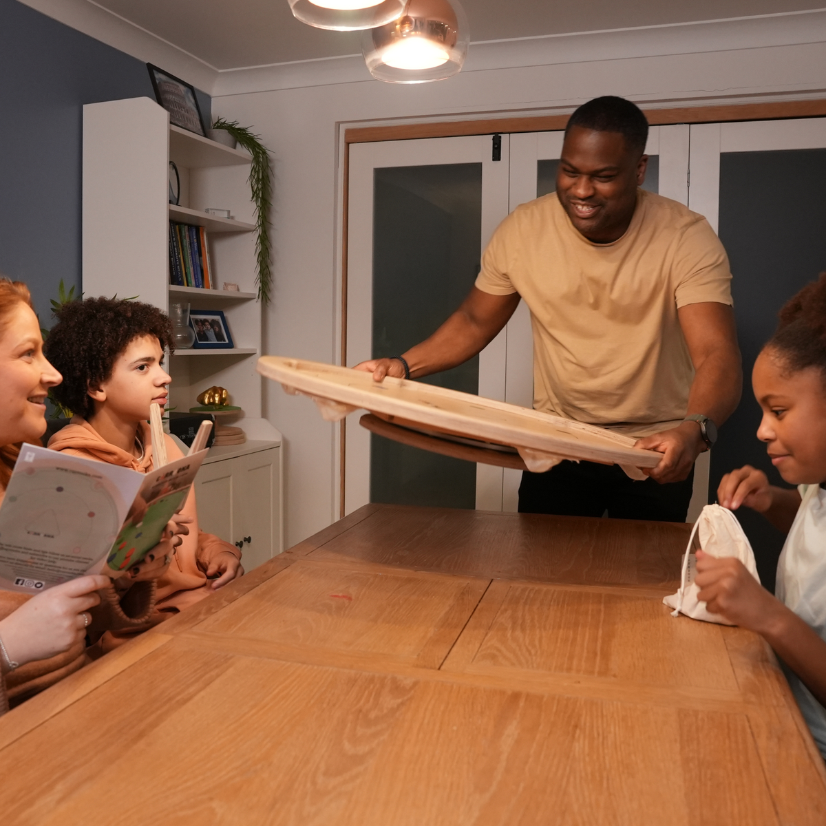 Gezin zet het Carrooka Natural bord op de eettafel en leest het instructieboekje