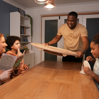 Gezin zet het Carrooka Natural bord op de eettafel en leest het instructieboekje