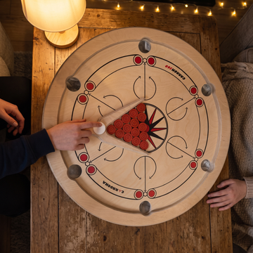 Carrooka Carrom 360 draaibord met rode fiches, gespeeld aan een houten salontafel