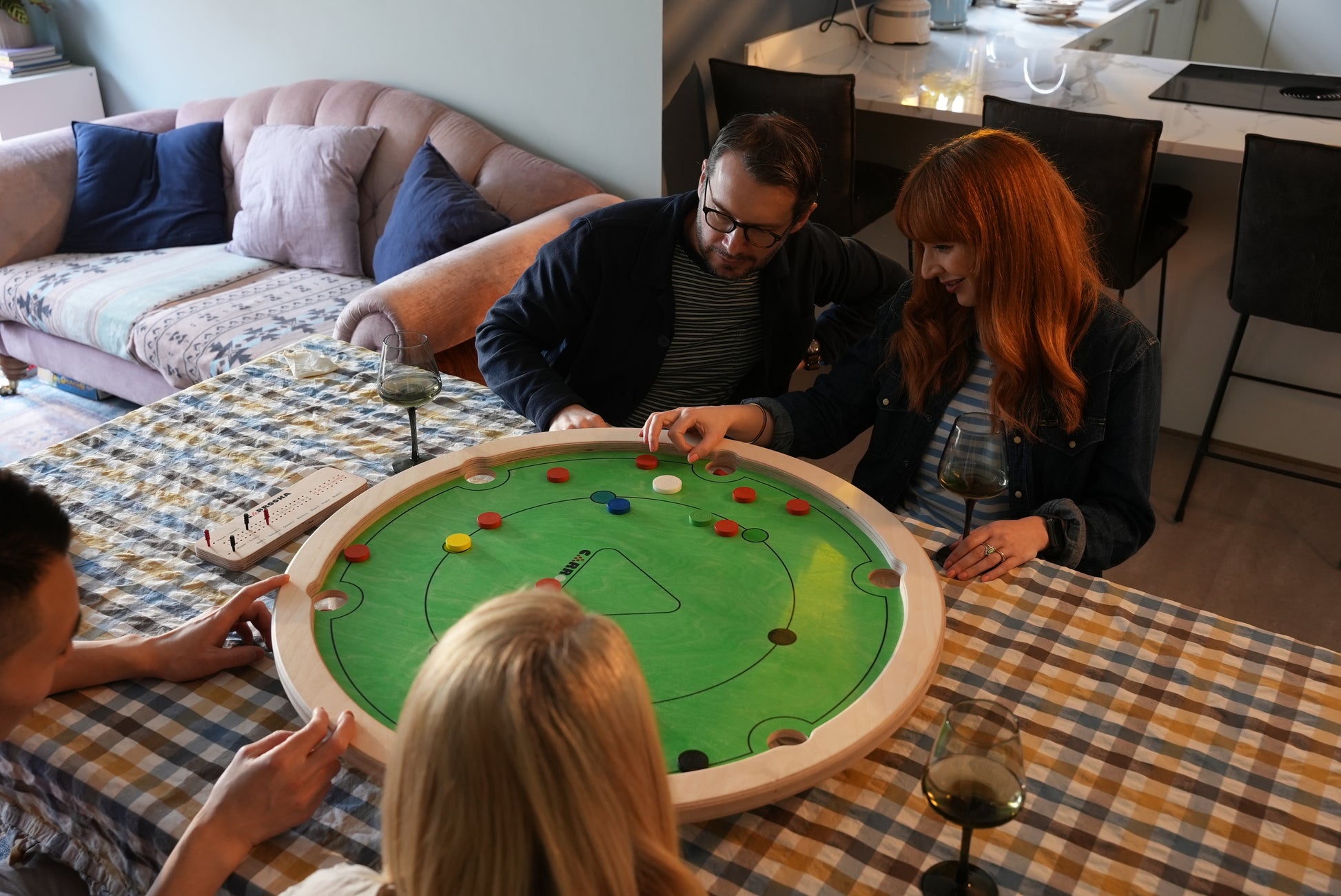 Groep vrienden speelt Carrooka Classic Groen in de woonkamer met een drankje erbij