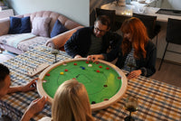 Groep vrienden speelt Carrooka Classic Groen in de woonkamer met een drankje erbij
