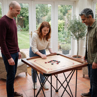 Drie vrienden spelen carrom op de Precise Carrom Champion 24mm World-Class Edition op de klapbare tafel in de tuinkamer