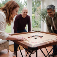 Vrouw schiet met de striker op het Precise Carrom bord World-Class Edition, twee vrienden kijken mee
